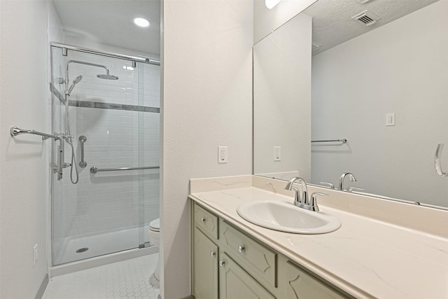 bathroom featuring a stall shower, visible vents, toilet, a textured ceiling, and vanity