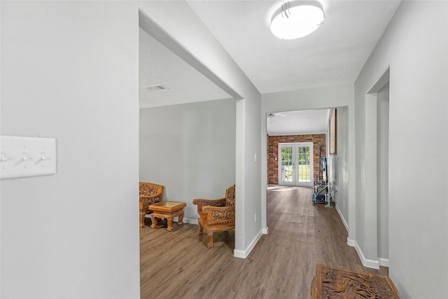 hallway featuring visible vents, baseboards, and wood finished floors