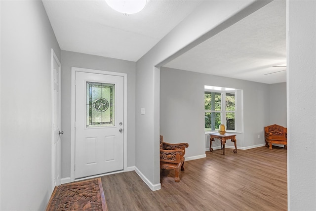 foyer with a textured ceiling, wood finished floors, and baseboards