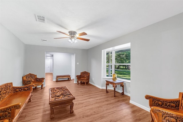 living area with a ceiling fan, light wood-type flooring, visible vents, and baseboards