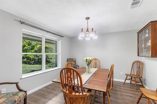 dining space with visible vents, a notable chandelier, baseboards, and wood finished floors