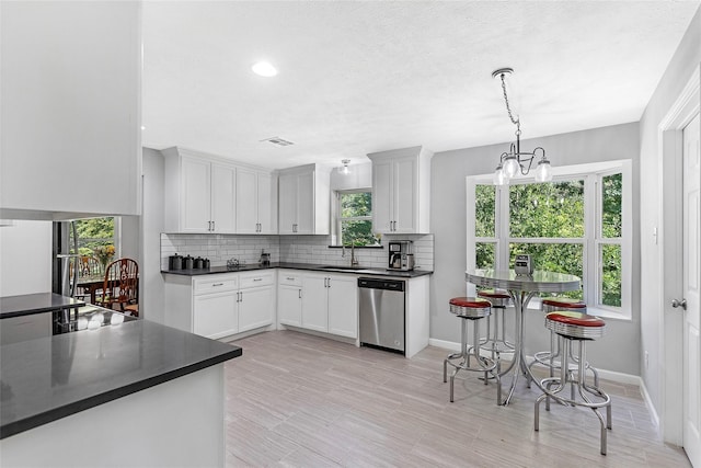 kitchen featuring a sink, dark countertops, tasteful backsplash, and dishwasher