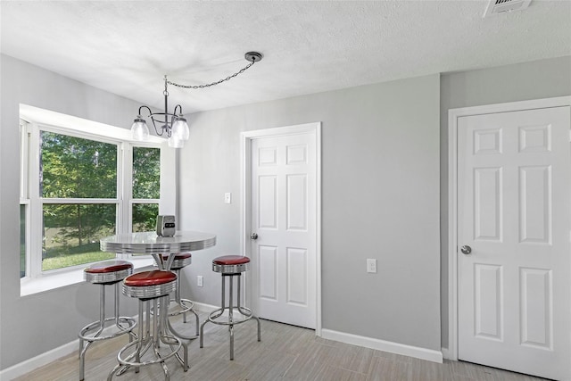 dining room featuring baseboards, visible vents, a chandelier, and a textured ceiling