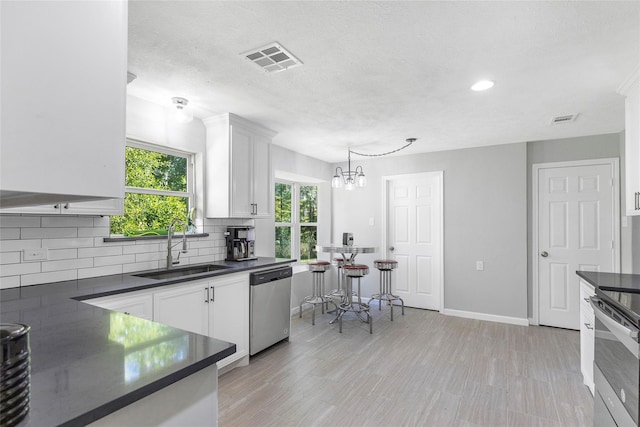 kitchen with dark countertops, visible vents, appliances with stainless steel finishes, and a sink