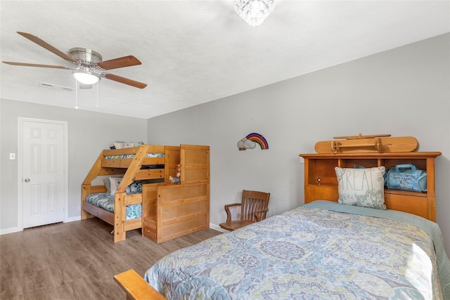 bedroom featuring a ceiling fan, visible vents, baseboards, and wood finished floors