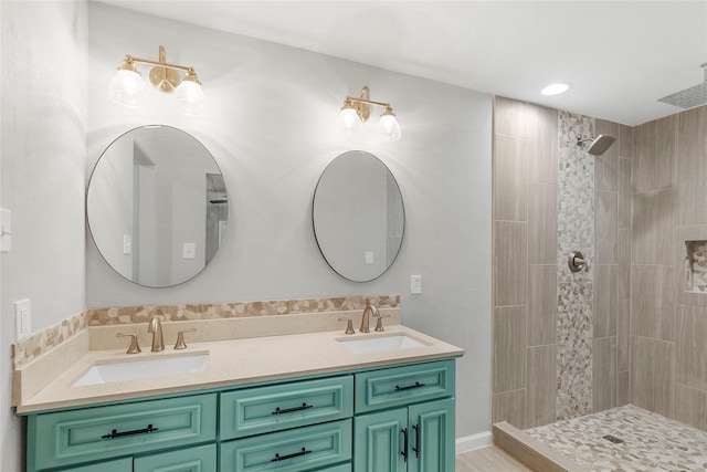 full bathroom featuring double vanity, tiled shower, and a sink