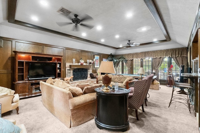 living room featuring a fireplace, a raised ceiling, visible vents, a ceiling fan, and light carpet