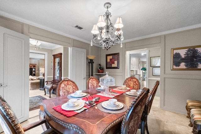 dining space with an inviting chandelier, visible vents, a decorative wall, and crown molding