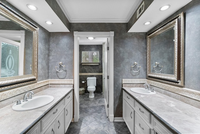 full bath featuring ornamental molding, two vanities, a sink, and toilet