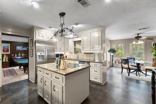 kitchen featuring tasteful backsplash, visible vents, white cabinetry, a kitchen island, and a sink