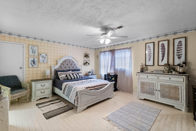 bedroom with light wood-style flooring, visible vents, a ceiling fan, and a textured ceiling