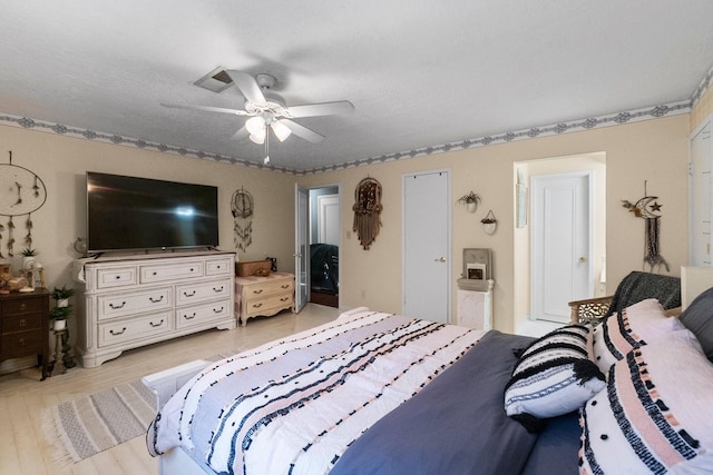 bedroom with a ceiling fan, light wood-type flooring, visible vents, and connected bathroom