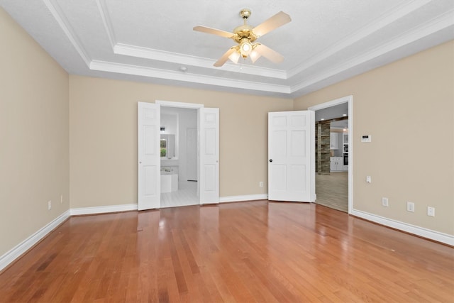 unfurnished bedroom featuring baseboards, a raised ceiling, wood finished floors, and ornamental molding