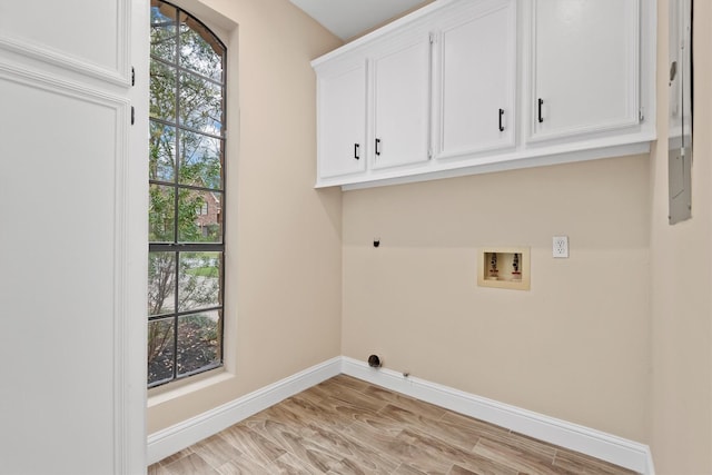 clothes washing area featuring cabinet space, baseboards, washer hookup, and light wood-style floors