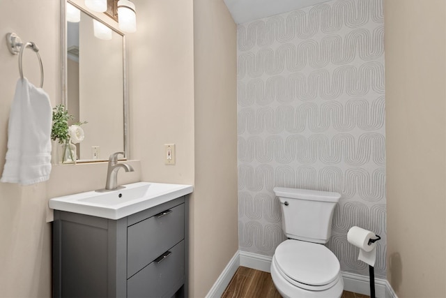 half bathroom featuring toilet, baseboards, wood finished floors, and vanity