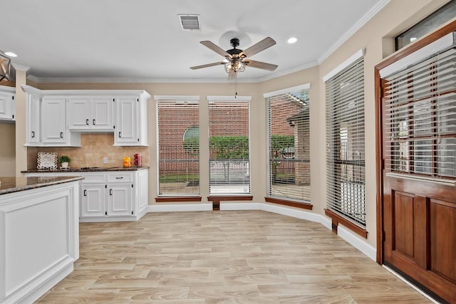 kitchen with visible vents, white cabinets, dark stone countertops, and ornamental molding