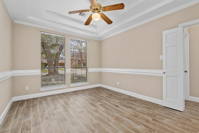 empty room featuring a raised ceiling, visible vents, and light wood finished floors