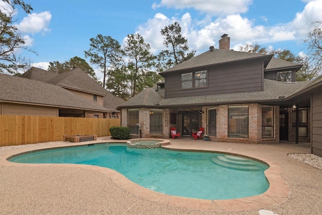 view of pool with a patio area, a pool with connected hot tub, and fence