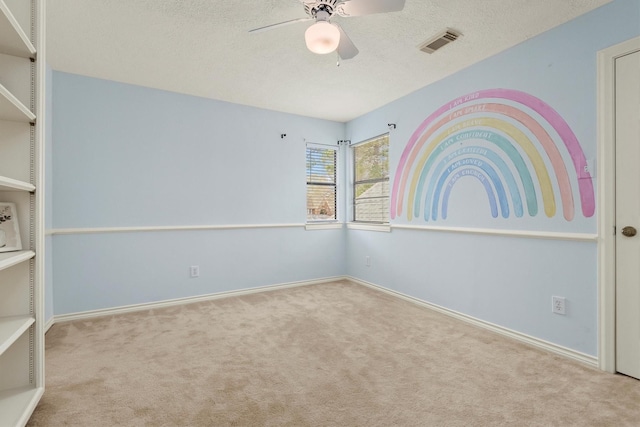 unfurnished room with visible vents, carpet flooring, ceiling fan, a textured ceiling, and baseboards