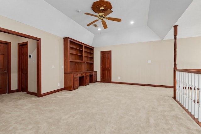 interior space featuring light carpet, vaulted ceiling, and built in desk