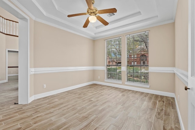 empty room with baseboards, visible vents, a tray ceiling, and wood finished floors