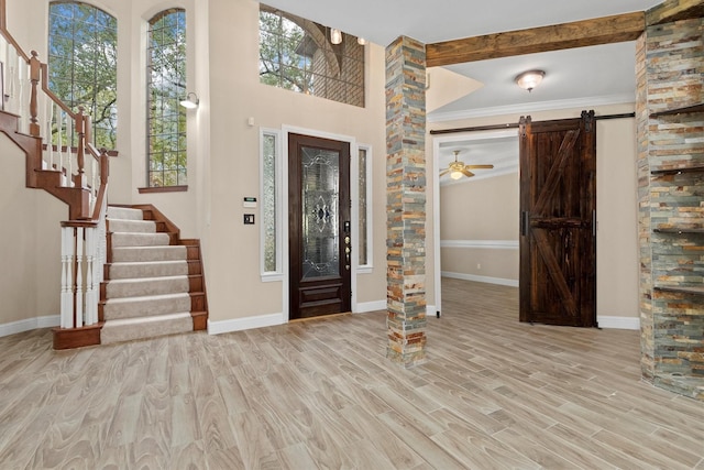 foyer with stairs, a barn door, wood finished floors, and baseboards