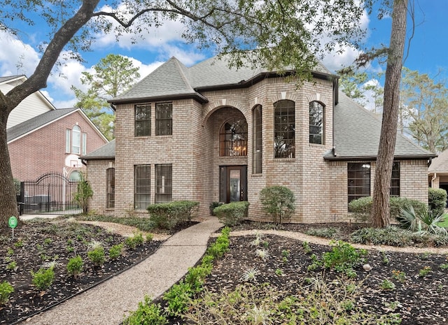 view of front of home with a shingled roof, a gate, and brick siding