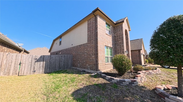 view of home's exterior featuring a yard, fence, and brick siding