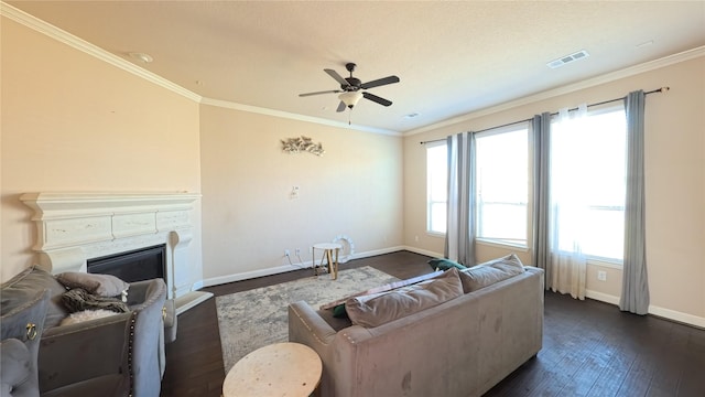 living room featuring visible vents, ornamental molding, and a glass covered fireplace