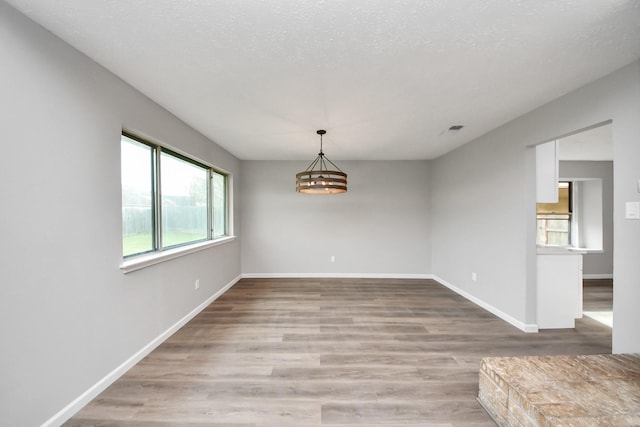 unfurnished dining area featuring visible vents, light wood-style floors, and baseboards