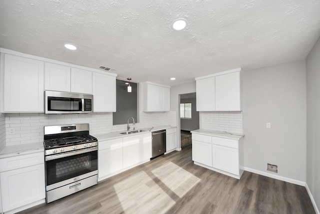 kitchen featuring wood finished floors, visible vents, appliances with stainless steel finishes, and a sink