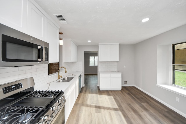 kitchen featuring light wood-type flooring, visible vents, a sink, white cabinetry, and stainless steel appliances