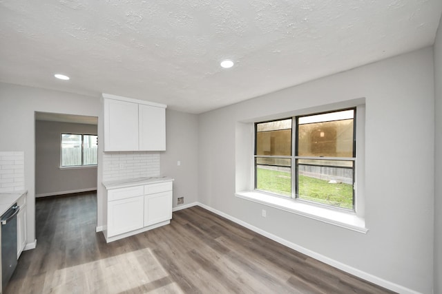 interior space with a wealth of natural light, decorative backsplash, wood finished floors, and white cabinets