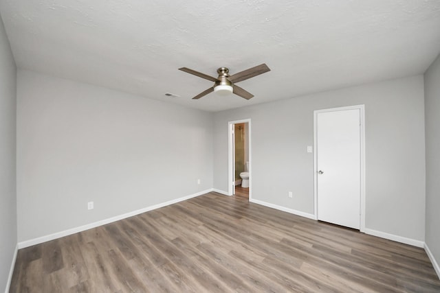 unfurnished bedroom with visible vents, ceiling fan, baseboards, ensuite bathroom, and wood finished floors