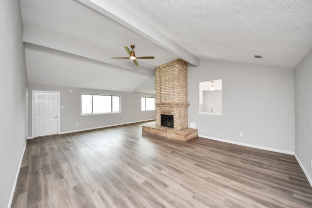 unfurnished living room with visible vents, a fireplace, vaulted ceiling with beams, and wood finished floors