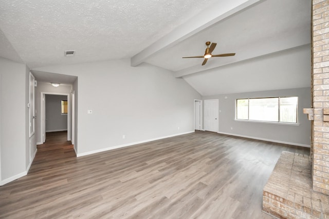 unfurnished living room featuring a textured ceiling, lofted ceiling with beams, baseboards, and wood finished floors