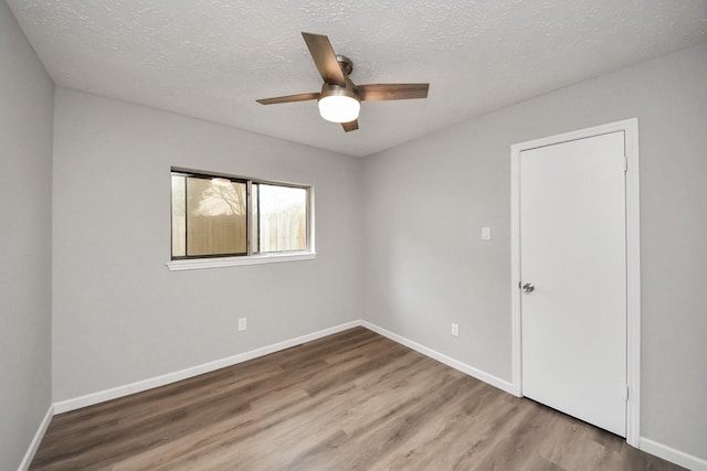 spare room featuring ceiling fan, wood finished floors, baseboards, and a textured ceiling