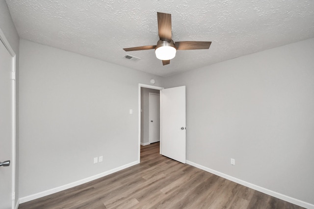 unfurnished bedroom with visible vents, a ceiling fan, a textured ceiling, wood finished floors, and baseboards