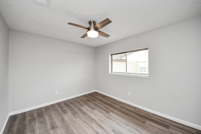 unfurnished room with a textured ceiling, baseboards, and wood finished floors