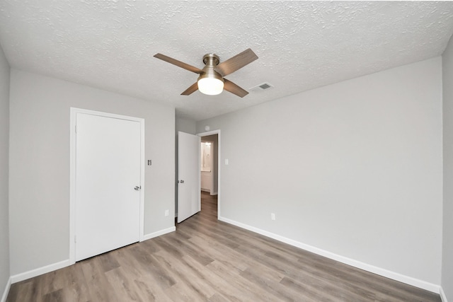 unfurnished bedroom with wood finished floors, visible vents, baseboards, ceiling fan, and a textured ceiling