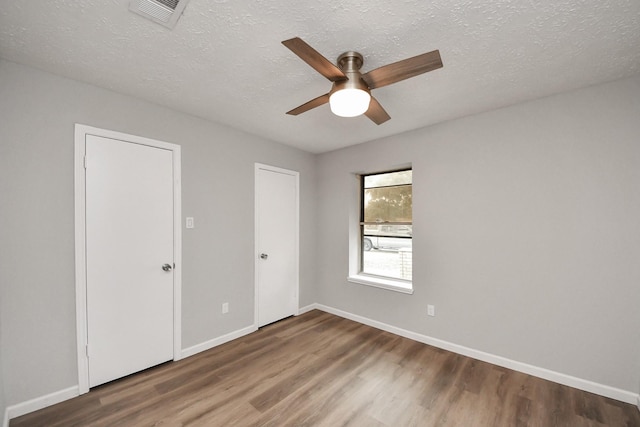 empty room with visible vents, baseboards, a textured ceiling, and wood finished floors