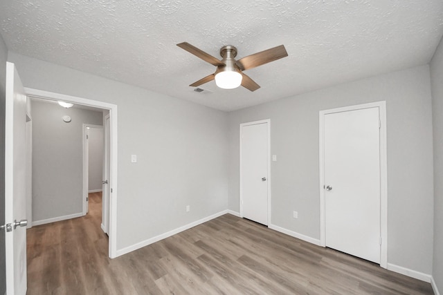 unfurnished bedroom with visible vents, baseboards, and wood finished floors