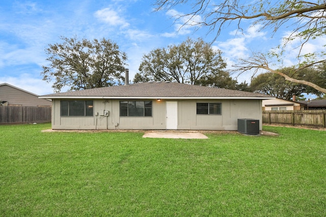 rear view of house with a fenced backyard, central AC unit, and a yard