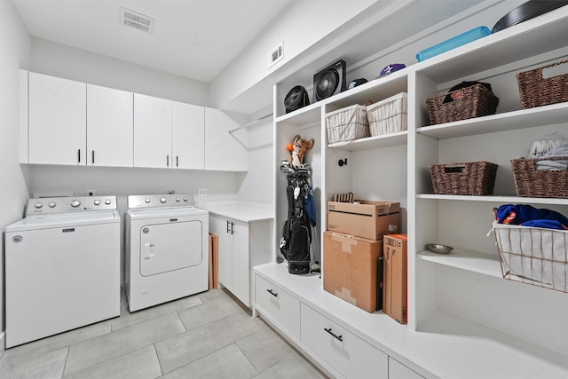 washroom with cabinet space, light tile patterned floors, visible vents, and separate washer and dryer