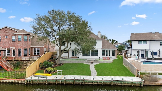 rear view of house featuring a water view, a fenced backyard, a lawn, and a patio