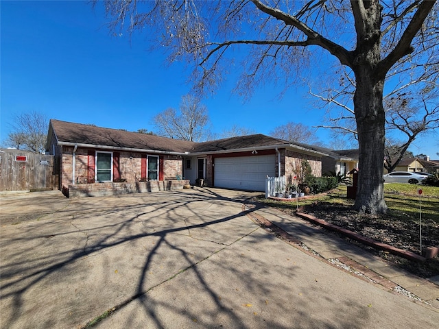 single story home featuring driveway, brick siding, an attached garage, and fence