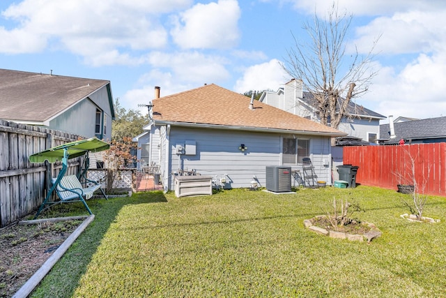 rear view of property featuring roof with shingles, a lawn, a fenced backyard, and central air condition unit