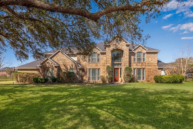 traditional-style home with a front yard, brick siding, and fence