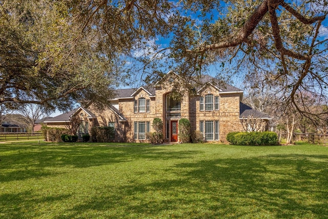 traditional home featuring stone siding, fence, and a front lawn