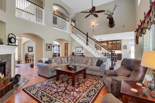 living room featuring arched walkways, a fireplace, wood finished floors, visible vents, and stairs